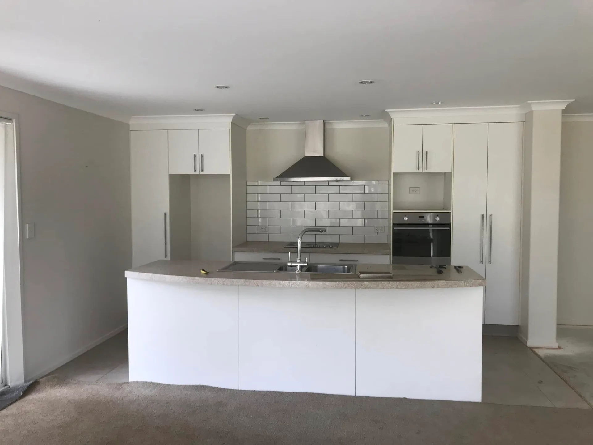 White island kitchen with subway tile splashback and overhead cabinetry