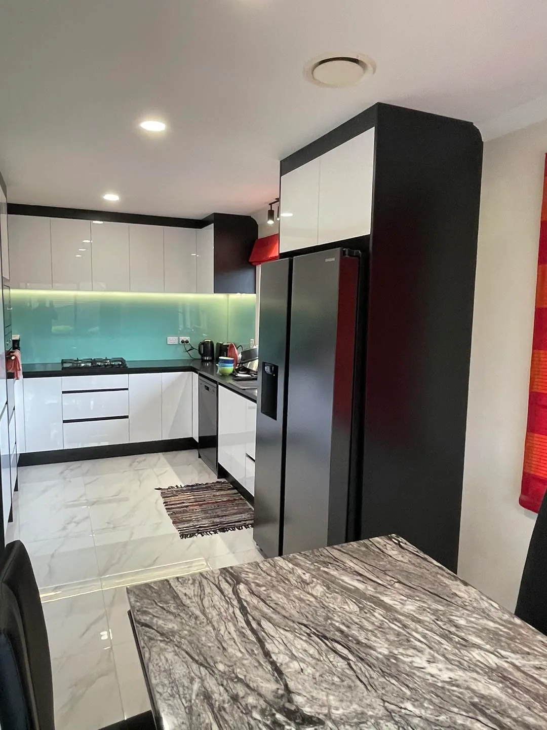 Bold black and white kitchen renovation with teal glass splashback